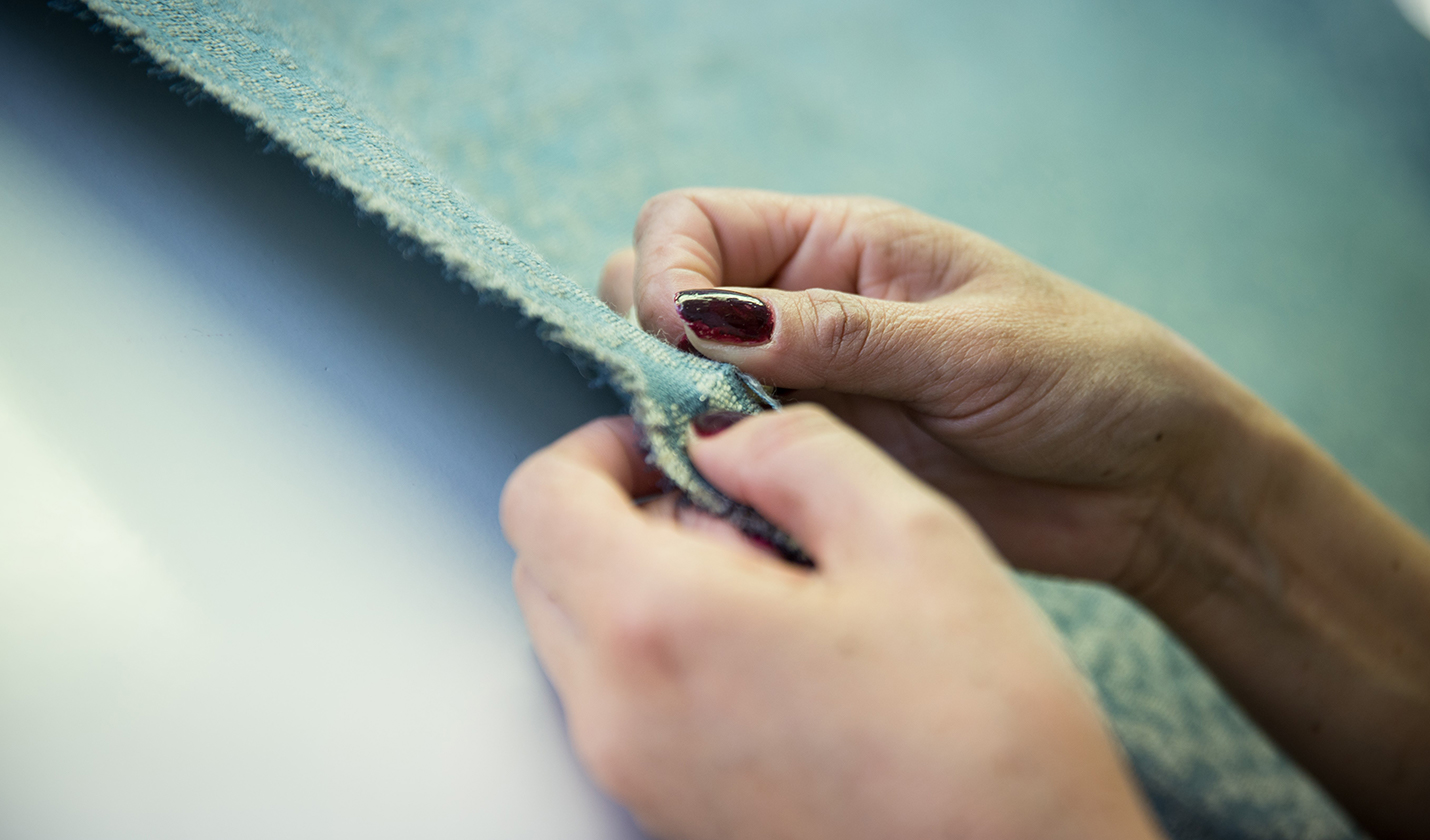 Hands of a woman sewing fabric with a needle.